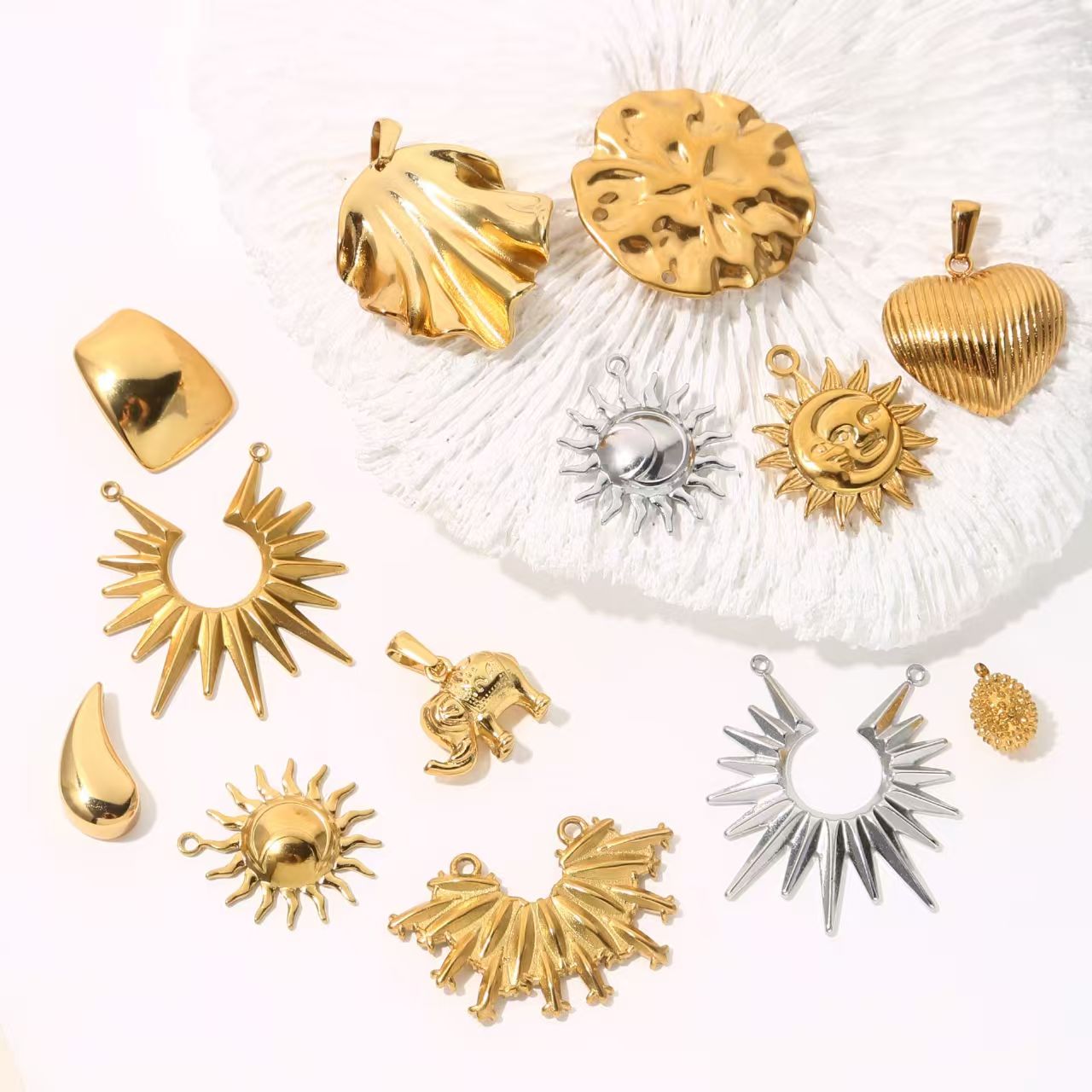 Collection of personalized gold - colored stainless - steel pendants. DIY jewelry accessories for bracelets and necklaces with multiple shapes like sun, heart, and elephant. 5 pieces in total.