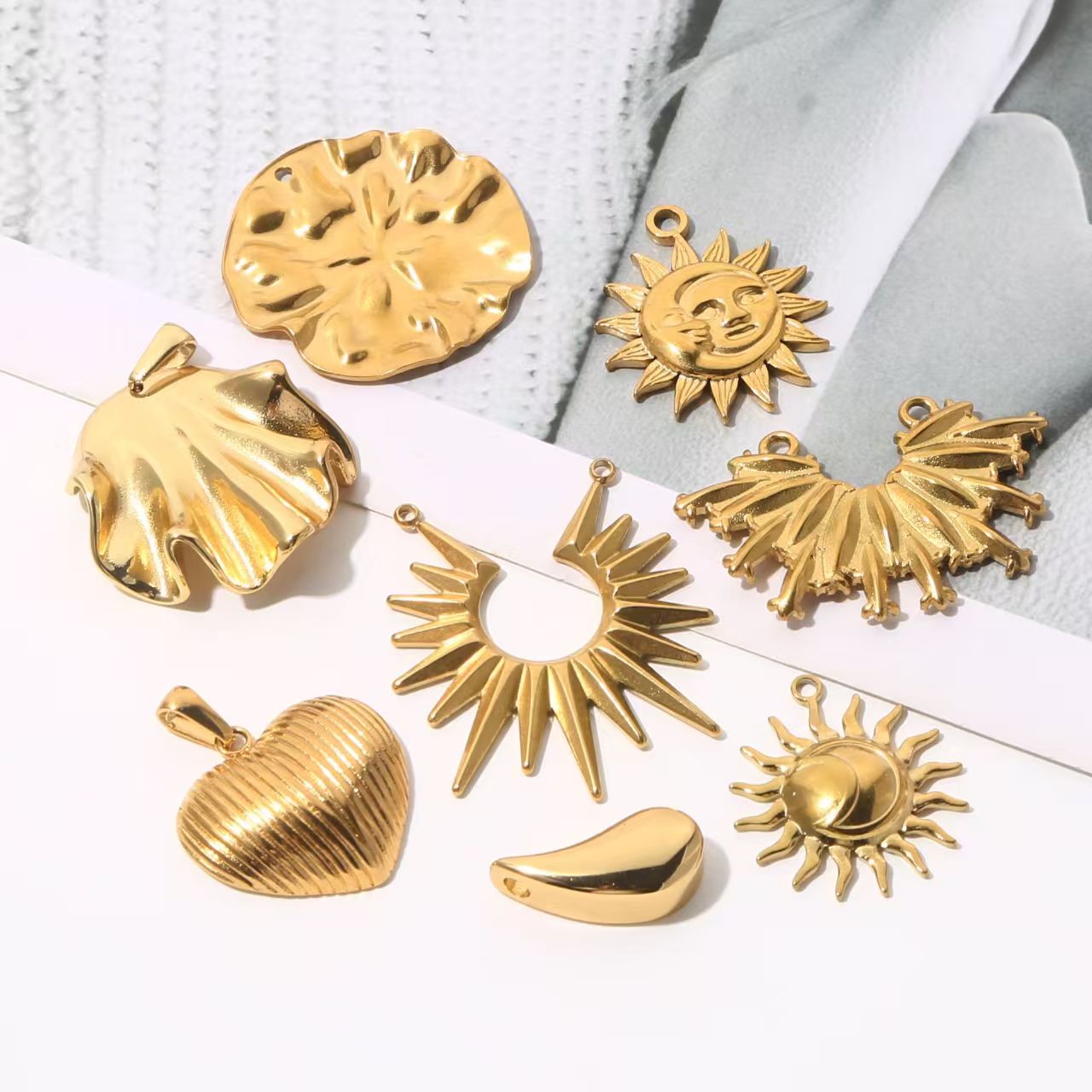 Collection of personalized gold - colored stainless - steel pendants. DIY jewelry accessories for bracelets and necklaces with multiple shapes like sun, heart, and elephant. 5 pieces in total.